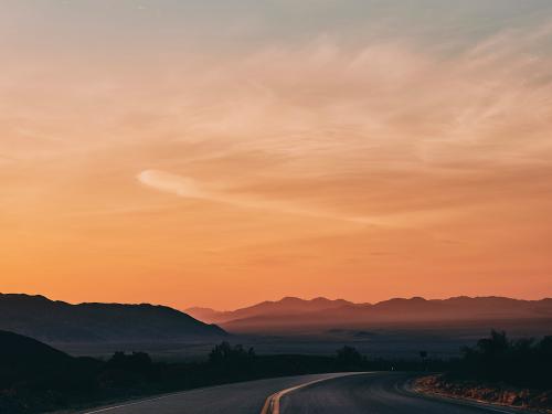 View down empty California road across the desert at sunset